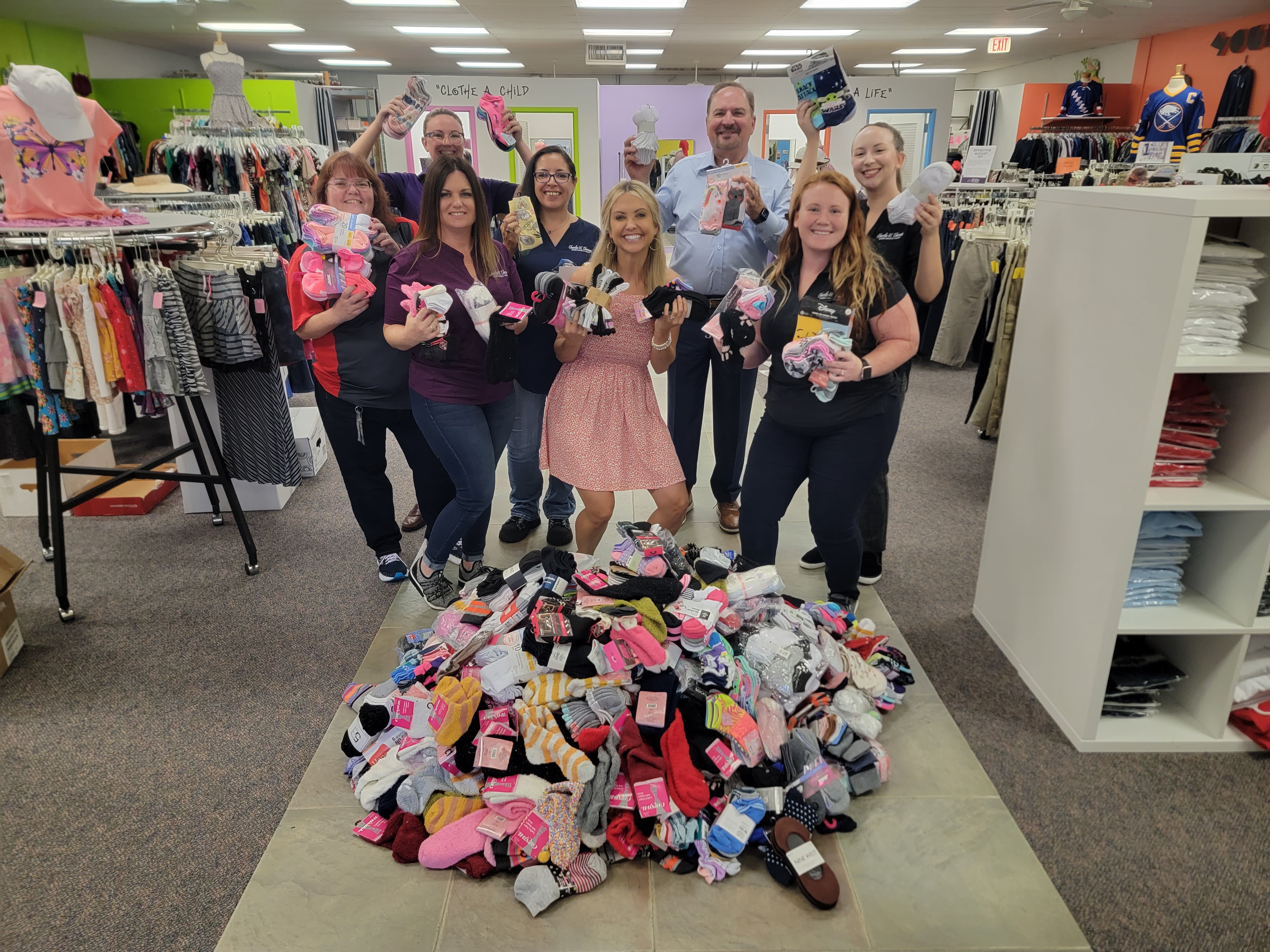 Tax Collector, Charles W.Thomas and team gathered around pile of sock donations with Clothes to Kids Director of Development, Megan DeBlasi.